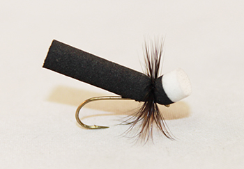 Ant Sailor Black dry fly with segmented black body, upright wing, and hackle for trout fishing.