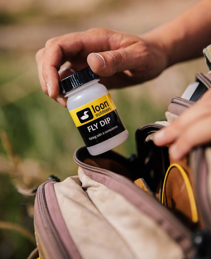 Bottle of Loon Fly Dip liquid floatant with applicator basket for treating dry flies.